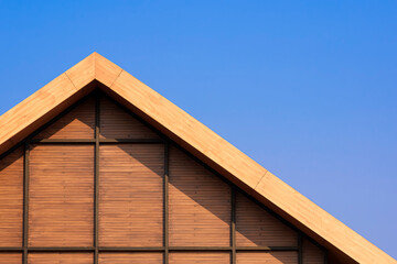 Part of vintage wooden gable roof with battens decoration against blue clear sky background