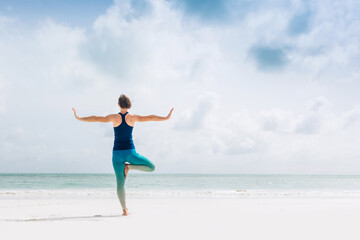 Caucasian woman practicing yoga at seashore
