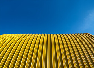 Yellow facade of sheet metal and blue sky from frog perspective. Yellow and blue contrasting on a...
