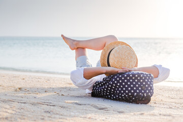 Summer beach vacation concept, caucasian woman with hat relaxing on the beach near ocean