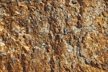 The surface of raw granite as a texture or background. One of the varieties of granite is brown-yellow.