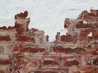 Détail en gros plan d'un reste de peinture blanche sur un vieux mur de briques rouges
