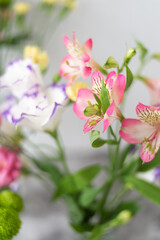 Obraz premium Colorful flowers composition over grey background with copy space. Fresh cut flowers for decoration home. Flower arrangement in a vase for home. Women's Day and spring time flower background
