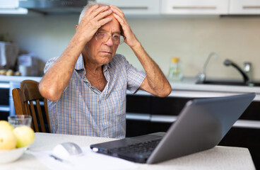 Modern elderly man sit at home having online consultation with doctor on computer, sick senior male talk on video call consulting using laptop. Healthcare concept