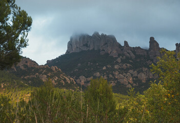 Fototapeta na wymiar View of Montserrat mountains covered by clouds in Catalonia, Spain with blue sky