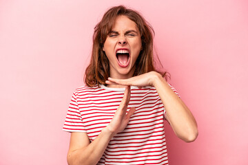 Young caucasian woman isolated on pink background showing a timeout gesture.