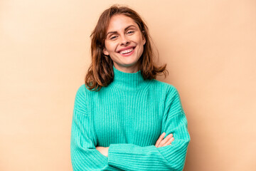Obraz premium Young caucasian woman isolated on beige background who feels confident, crossing arms with determination.