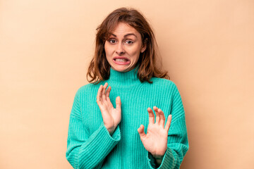 Young caucasian woman isolated on beige background rejecting someone showing a gesture of disgust.