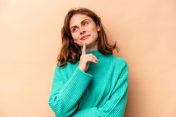 Young caucasian woman isolated on beige background contemplating, planning a strategy, thinking about the way of a business.