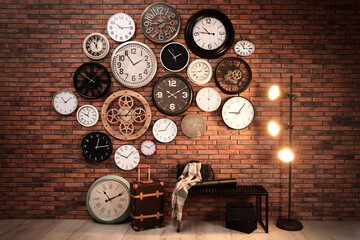 Collection of clocks hanging on red brick wall indoors