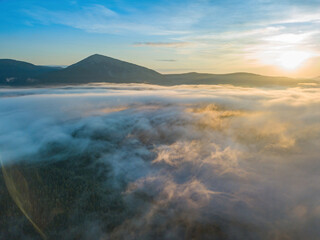 Obraz premium The rays of dawn over the fog in the Ukrainian Carpathians. Aerial drone view.