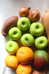 Green apples, oranges, mango, butternut squash, onion and sweet potato on the table. Flat lay.