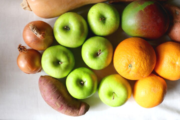 Green apples, oranges, mango, butternut squash, onion and sweet potato on the table. Flat lay.