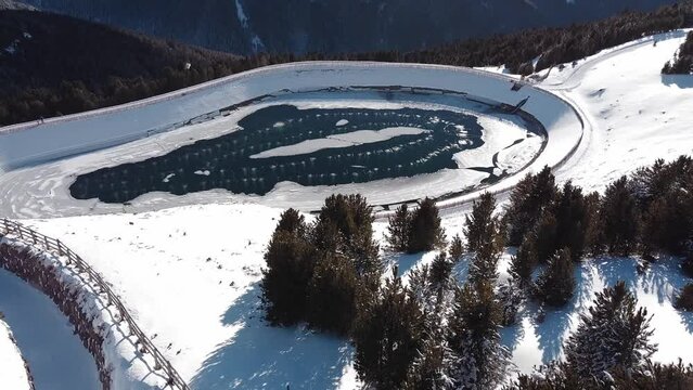 Aerial landscape view over a frozen lake in the snow capped italian alps, in winter