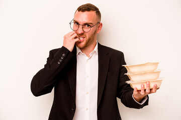 Young business caucasian man holding tupperware isolated on white background biting fingernails, nervous and very anxious.
