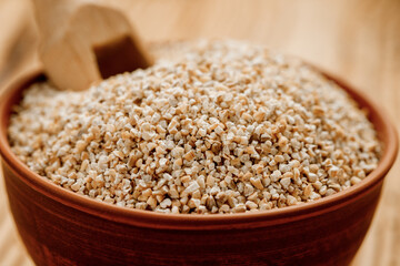 Barley groats in bowls and bags on a wooden background. High quality photo - obrazy, fototapety, plakaty