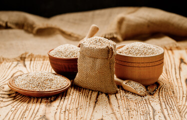 Fototapeta na wymiar Barley groats in bowls and bags on a wooden background. High quality photo
