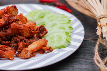 Fried Pork Belly with Fish Sauce and Sticky Rice Served on a white plate on a black wooden floor.