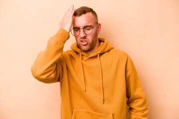 Young caucasian man isolated on beige background forgetting something, slapping forehead with palm...