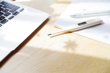 家で体温計で検温する。パソコンと筆記具