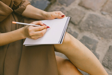 Cropped photo of a woman's hand with a pensil writing in a notebook