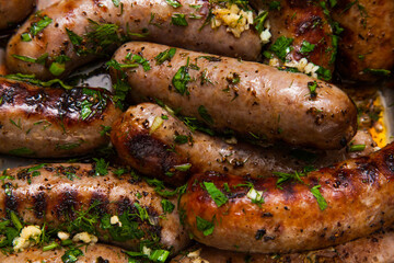 Grilled sausages with onions and garlic, sprinkled with parsley and dill closeup.