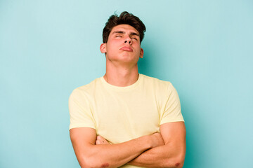 Young caucasian man isolated on blue background tired of a repetitive task.