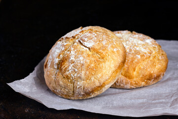 Fresh homemade crisp bread. Healthy baked bread on Kraft paper over black rustic wooden table.