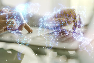 Double exposure of abstract digital world map and hand typing on laptop on background, research and strategy concept