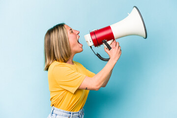 Young caucasian woman holding a megaphone isolated on blue background