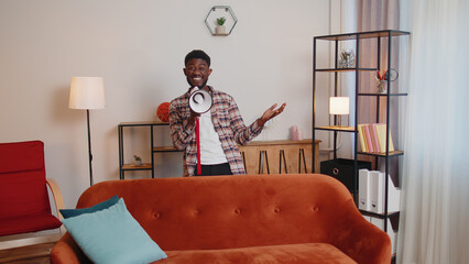 Young african american man scream shout in megaphone loudspeaker announces discounts sale of real...