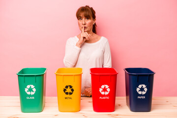 Middle age woman recycling isolated on pink background keeping a secret or asking for silence.