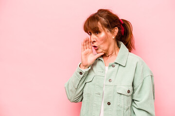 Middle age caucasian woman isolated on pink background being shocked because of something she has seen.