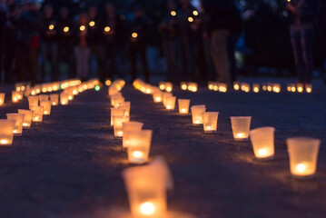 A group of candles burning in street and people in the background.