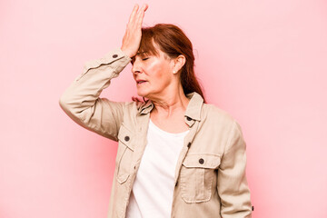 Middle age caucasian woman isolated on pink background forgetting something, slapping forehead with...