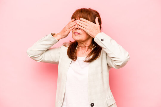 Middle age caucasian woman isolated on pink background afraid covering eyes with hands.