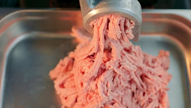 Production of minced meat in industry. Meat combine grinds pieces of meat.