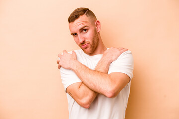 Young caucasian man isolated on beige background hugs, smiling carefree and happy.