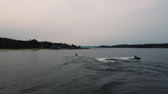 Guys riding jet skis on blue water in Sweden. Drone flying over jet skis