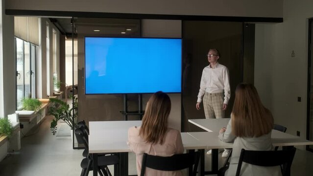 Diverse office conference room meeting: male project manager uses Chroma Key wall mounted blue screen TV to present an investment project. Project presentation. The concept of business, training
