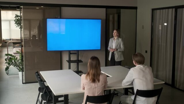 Diverse office conference room meeting: female project manager uses Chroma Key wall mounted blue screen TV to present an investment project. Project presentation. Business concept, training