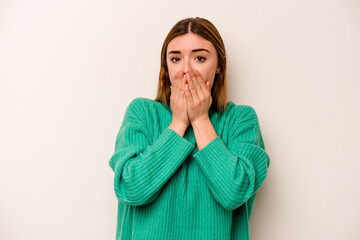 Young caucasian woman isolated on white background covering mouth with hands looking worried.