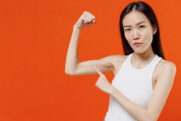 Confident young woman of Asian ethnicity 20s years old in white tank top showing pointing...
