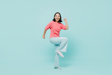 Fototapeta na wymiar Full body side view young happy woman of Asian ethnicity 20s in pink sweater look camera do winner gesture raise up leg isolated on pastel plain light blue background studio People lifestyle concept.