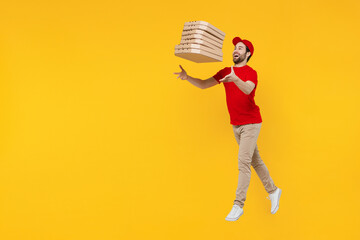Side view full body delivery guy employee man in red cap T-shirt uniform work as dealer courier hold toss up pizza in cardboard flatbox jump high isolated on plain yellow background Service concept