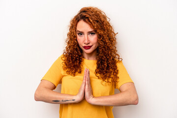 Young ginger caucasian woman isolated on white background praying, showing devotion, religious...