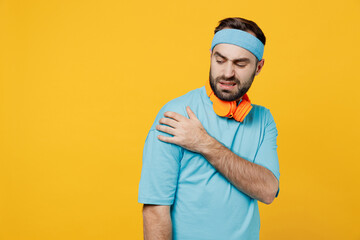 Young sick ill sad displeased fitness trainer instructor sporty man sportsman in headband blue t-shirt hold place of ache pain isolated on plain yellow background. Workout sport motivation concept