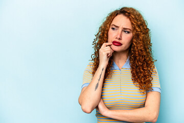 Young ginger caucasian woman isolated on blue background looking sideways with doubtful and skeptical expression.