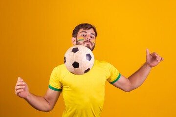 Young handsome boy fan of Brazil playing with a soccer ball