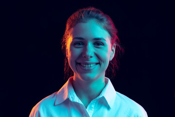 Half-length portrait of young pretty girl in white shirt isolated on dark background in blue neon...